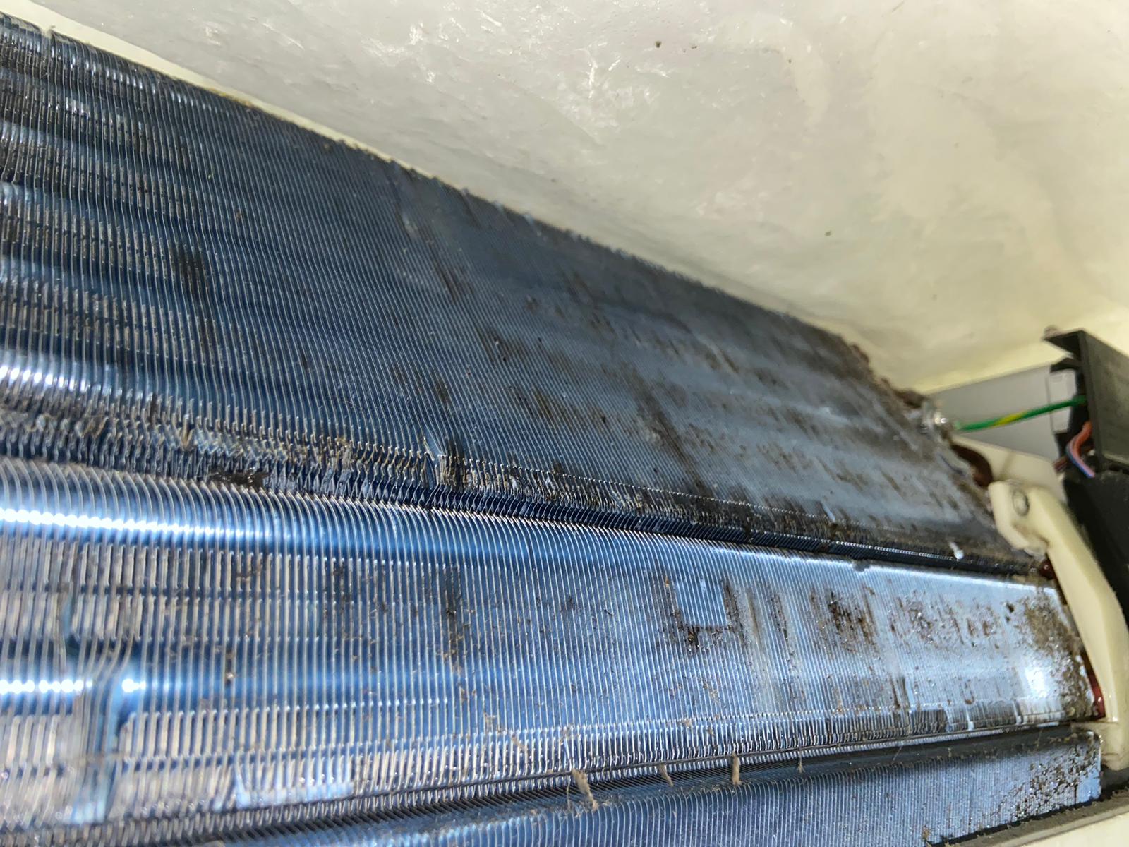 清洗前嘅冷氣機蒸發器，表面積聚黑色污垢同鏽跡