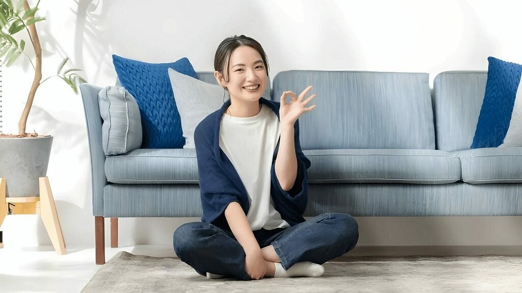 一個人在藍色沙發前盤腿而坐,用手腕比出「OK」衛生間。有效的除甲醛方法正在使用中。
