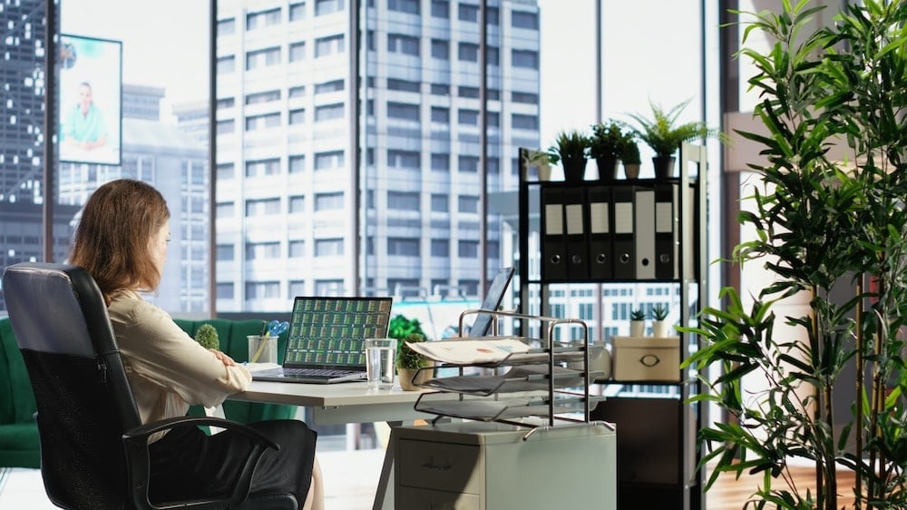 女上班族坐在現代辦公室內，辦公桌上整齊擺放文件與水晶植物，展現良好的辦公室風水布局
